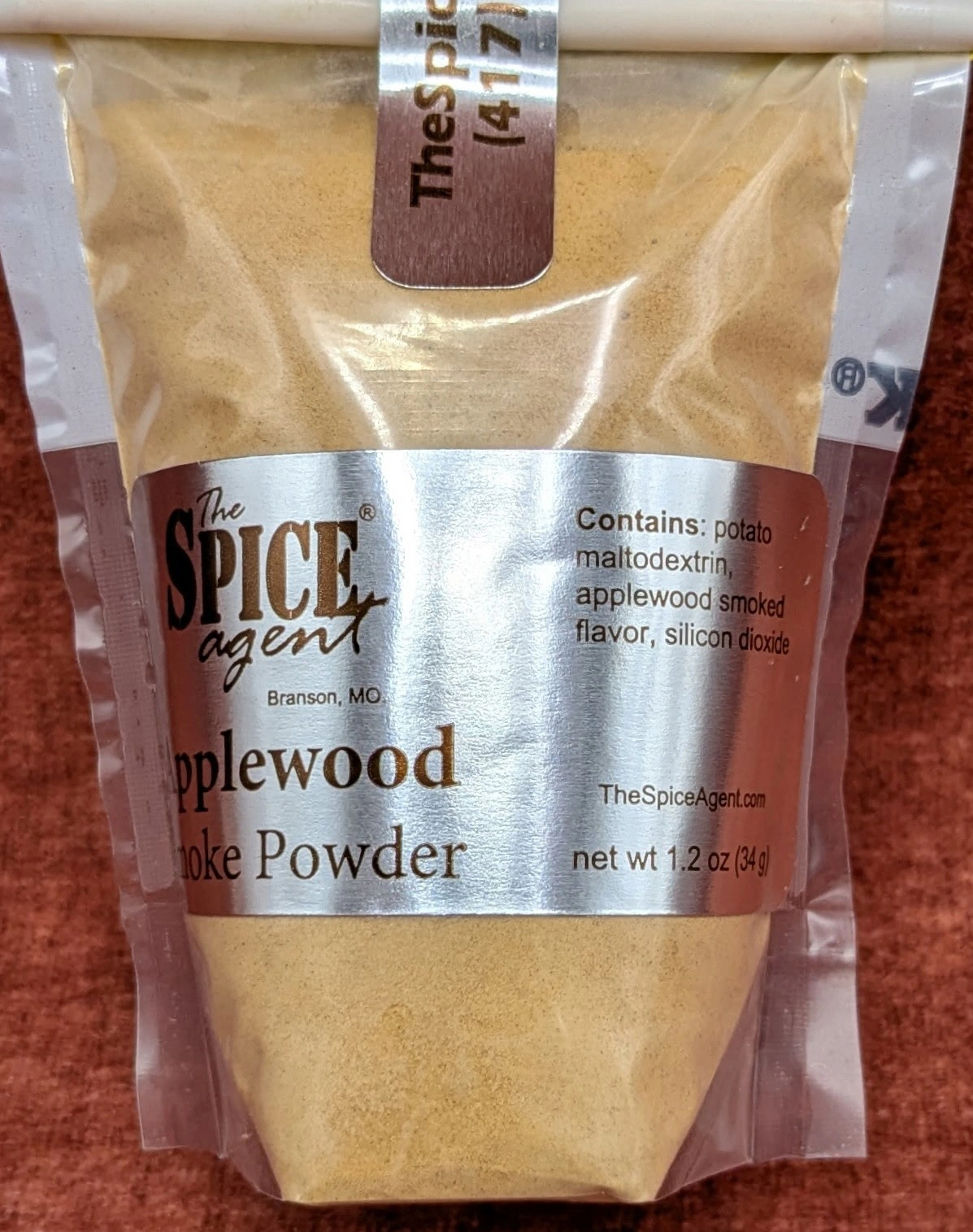 Clear refill bag of Applewood Smoke Powder on warm rust textile